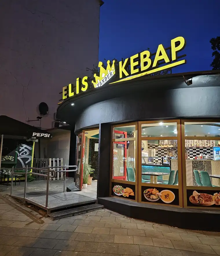 Lokal ELİS KEBAP wieczorem — złoty neon z koroną nad witryną