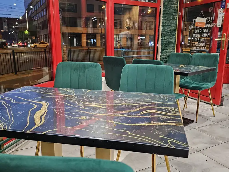 Zielone welurowe krzesła przy czerwonych oknach